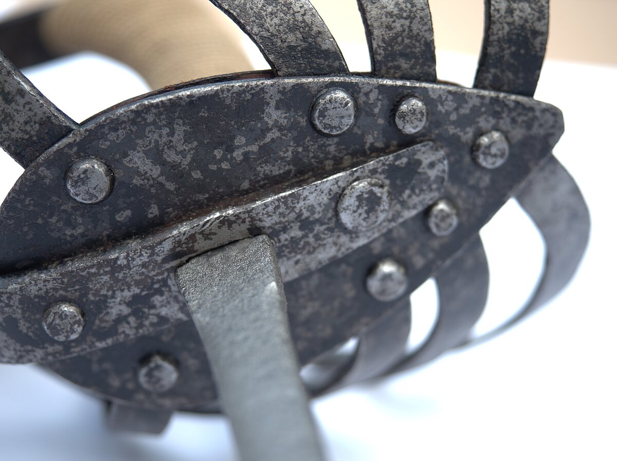 7. att. Rapiera šķērša daļa pēc korozijas slāņu noņemšanas un daļēji saglabājušos krāsojuma slāni. Foto: Gints Ajausks 7. att. Rapiera šķērša daļa pēc korozijas slāņu noņemšanas un daļēji saglabājušos krāsojuma slāni. Foto: Gints Ajausks