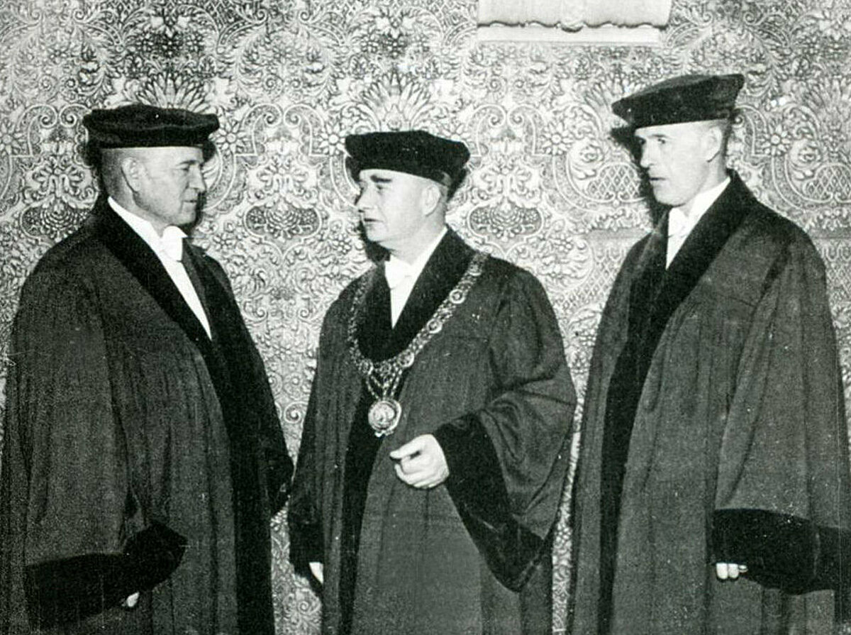 Foto no Latvijas Universitātes muzeja. Latvijas Universitātes vadība jaunajos amata tērpos. Attēlā redzams (no kreisās uz labo) prorektors saimniecības lietās prof. Dr. Jānis Kārkliņš, prorektors studentu lietās prof. Dr. Alfrēds Vītols un LU rektors prof. Dr. Mārtiņš Prīmanis.